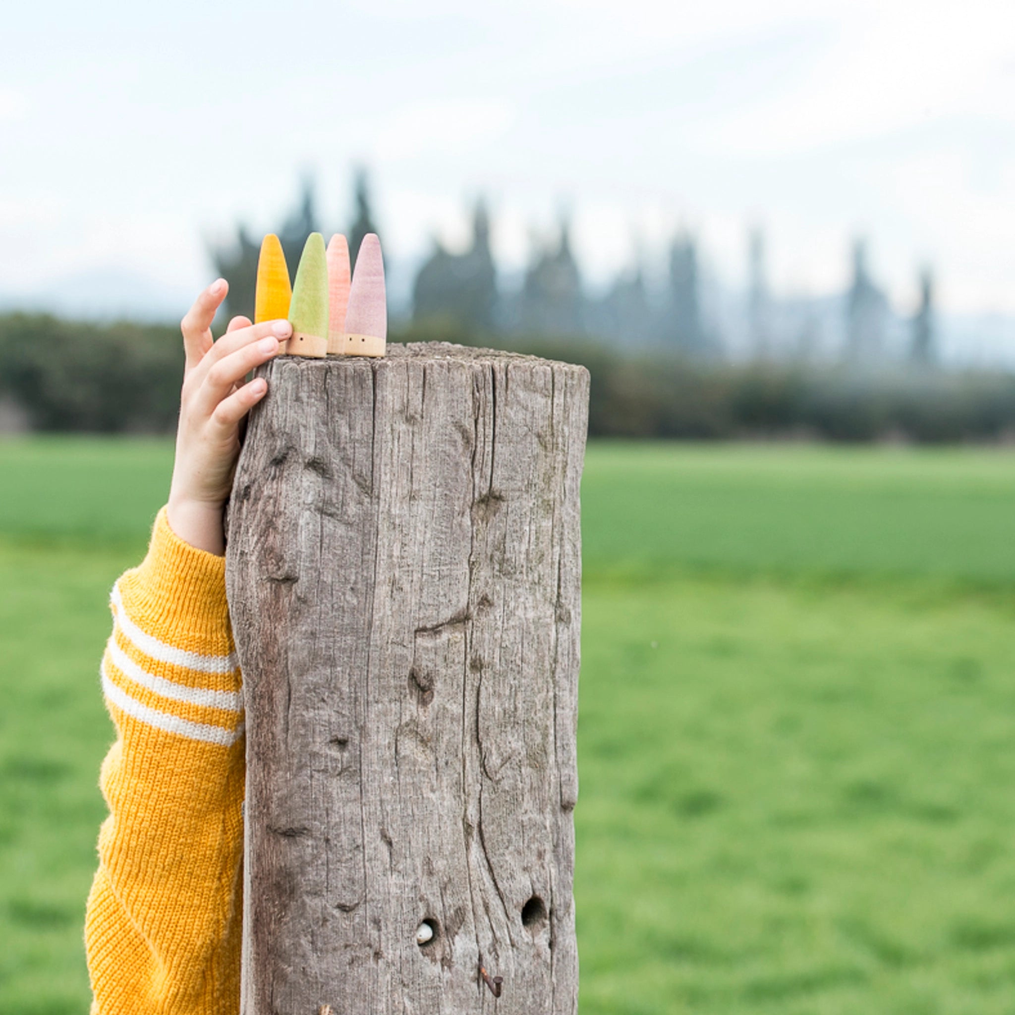 Freies Spiel: Sticks – Eine Hand hält bunte, handgefertigte Holzfiguren aus nachhaltiger Forstwirtschaft. Ideal für kreatives Kinderspiel, gefertigt in Spanien.