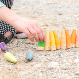 Freies Spiel: Sticks – Eine Hand berührt handgefertigte Holzfiguren. Dieses nachhaltige Set aus 18 Sticks-Figuren, ideal für kreatives Kinderspiel, strahlt spielerische Einfachheit und spanische Handwerkskunst aus.