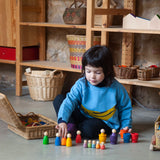 Freies Spiel: Baby Nins in einer Kokosnussschale, aus nachhaltig geforstetem Holz, handgefertigt in Spanien. Ein Kind spielt fröhlich mit den Baby Nins-Figuren, ideal für kreatives Kinderspiel.