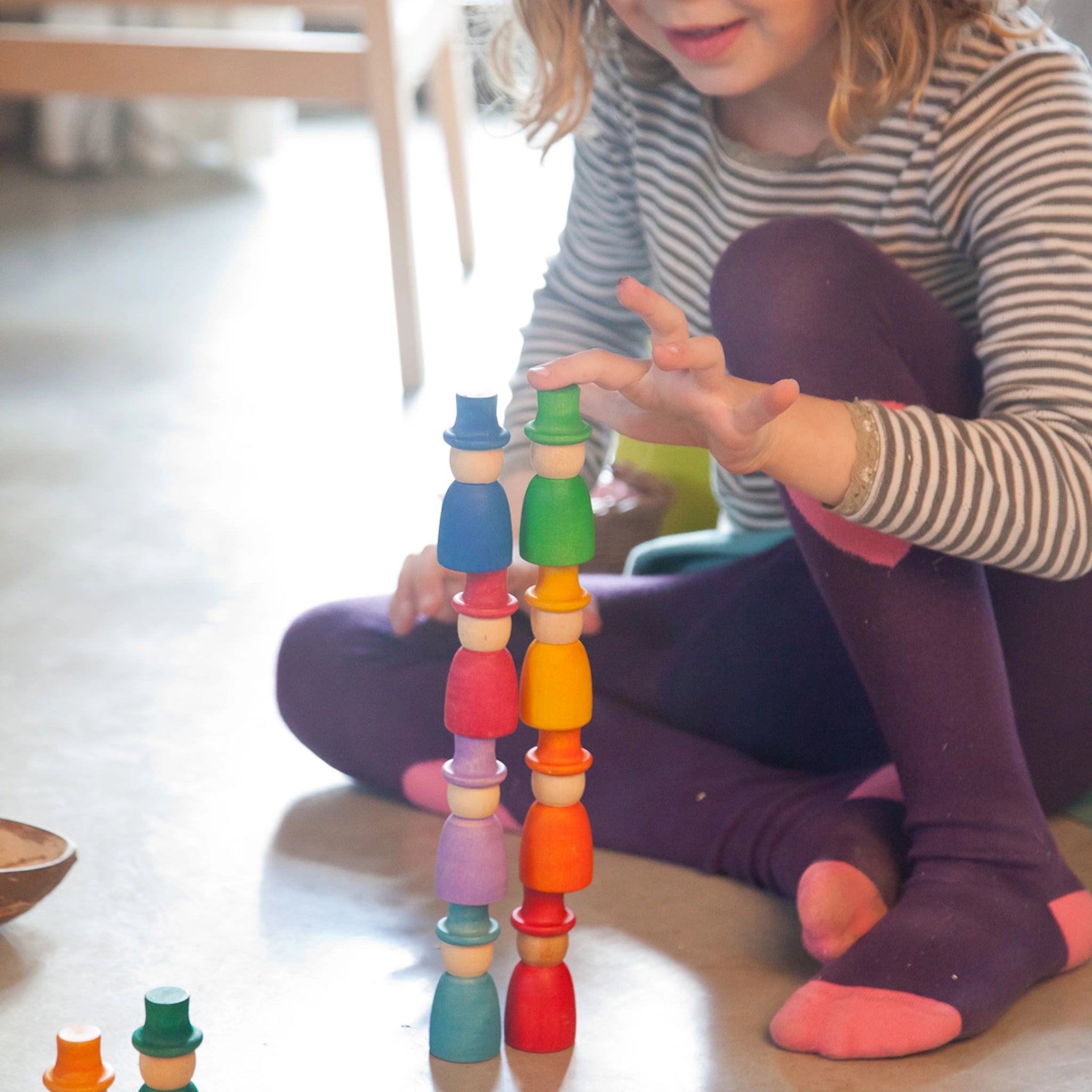 Mädchen spielt mit Freies Spiel: Wizards, einem Set aus 12 handgefertigten, bunten Holzfiguren ideal für kreatives Spiel, aus nachhaltiger Produktion bei KLICKKLACK.