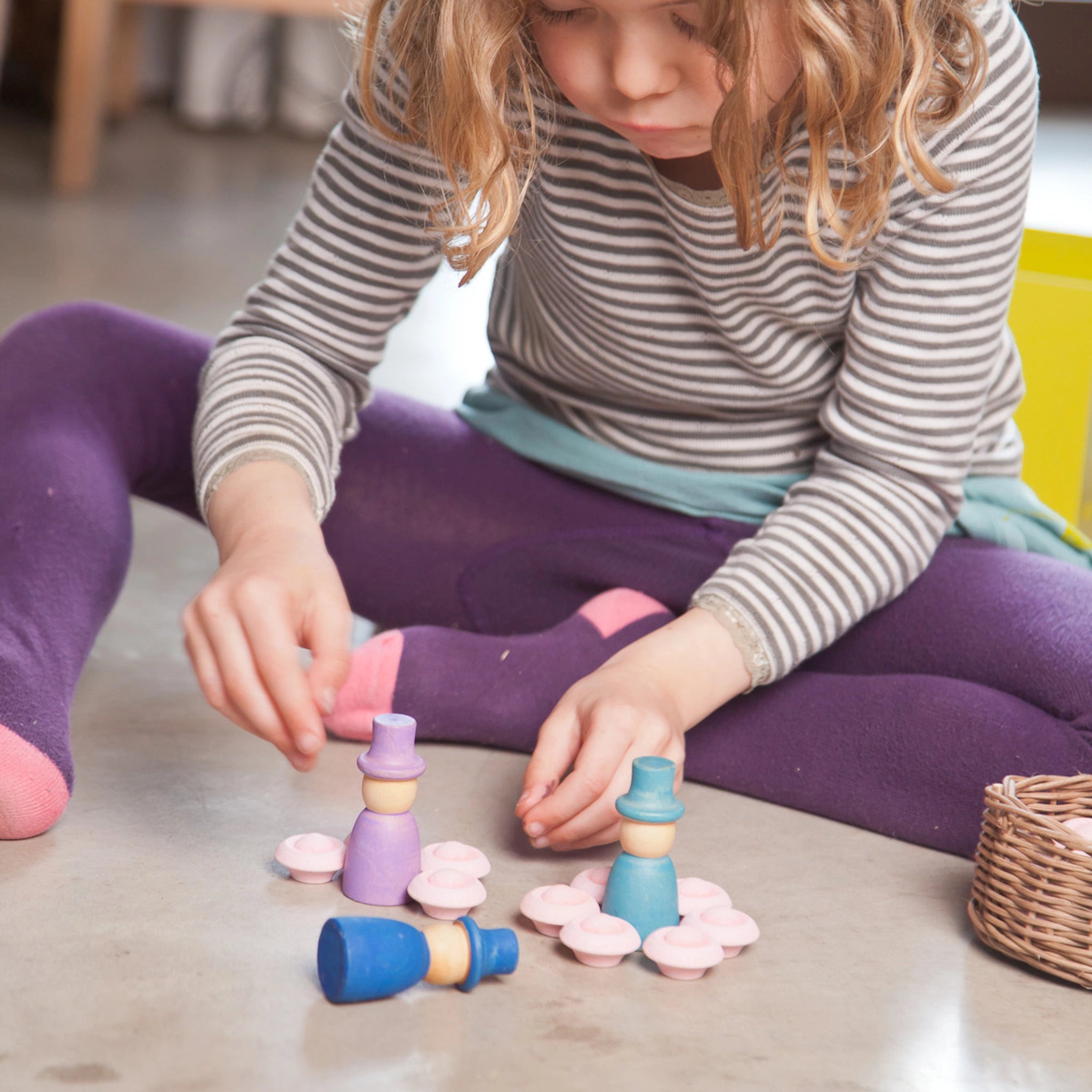 Ein Mädchen spielt mit Freies Spiel: Wizards, einem Set aus 12 handgefertigten Zauberer-Figuren aus nachhaltig geforstetem Holz, ideal für kreatives, freies Spiel.