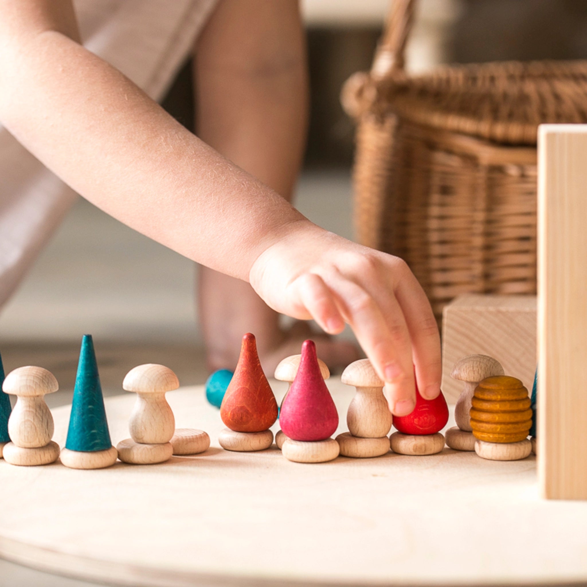 Ein Kind spielt mit dem Freies Spiel: Nins Tomten Set aus sechs handgefertigten Zwergfiguren, gefertigt aus nachhaltig geforstetem Holz, ideal für freies Spielen.