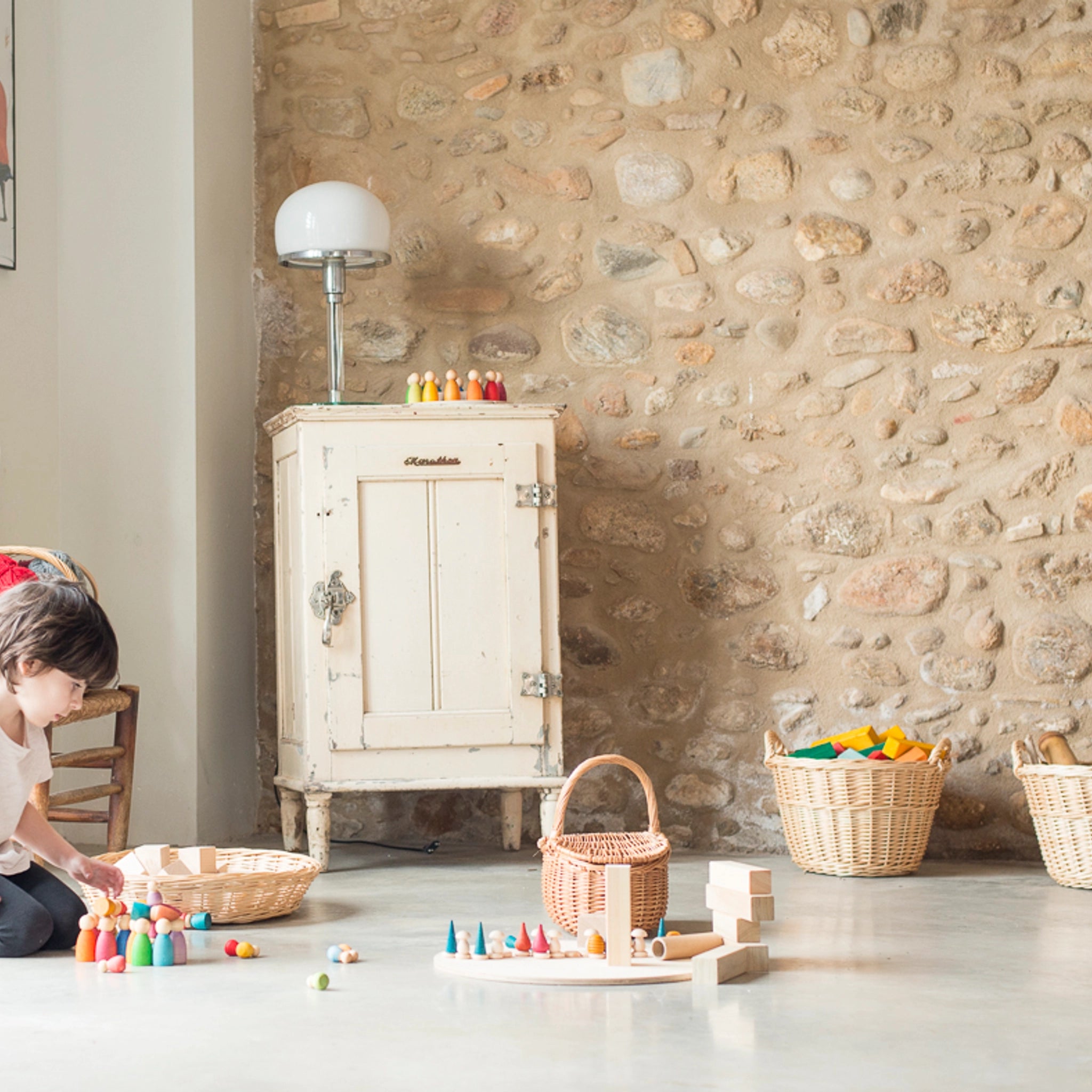 Freies Spiel: Nins Tomten – Ein Kind spielt im Zimmer mit handgefertigten Nins-Zwergfiguren aus nachhaltigem Holz, ideal für kreatives Spiel. Sichtbar ist ein Set mit passendem Wichtelzubehör.