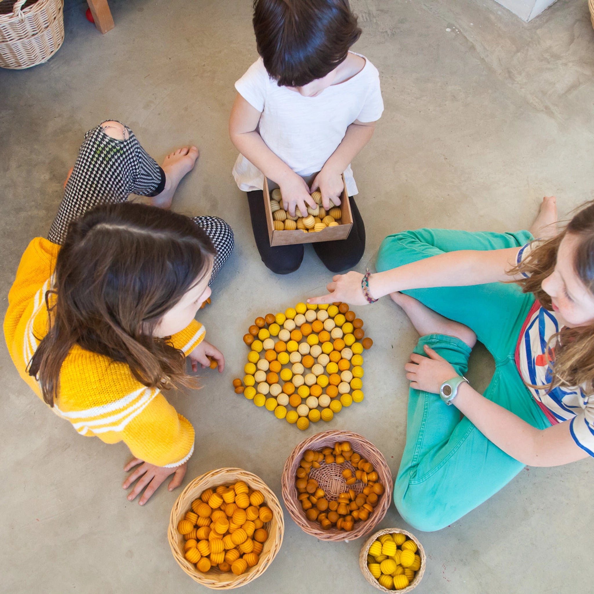 Kinder spielen mit dem Freies Spiel: Mandala Honeycomb Set, das aus 36 handgefertigten, honigwabenförmigen Holzstücken besteht, ideal für kreative Muster und Landschaften.