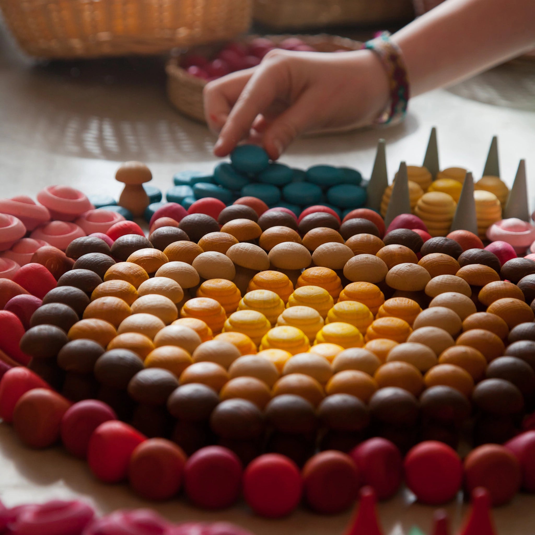 Freies Spiel: Mandala Mushroom – Eine Hand berührt ein handgefertigtes Holzpilz-Set, ideal für kreative Mandalas und Kunstwerke. Perfekt für nachhaltiges, freies Spielen von Kindern, hergestellt in Spanien.