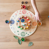 Freies Spiel: Seasons & Elements Platform aus handgefertigtem Holz, verziert mit saisonalen Motiven. Ideal zum kreativen Spielen, gezeigt mit bunten Spielmaterialien auf einer großen Holzplatte, passend für KLICKKLACKs nachhaltiges Angebot.