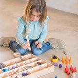 Mädchen spielt am Boden mit dem handgefertigten Freies Spiel: Tinker Tray aus nachhaltig geforstetem Holz, ideal für kreatives Spiel und Ordnung, hergestellt in Spanien.