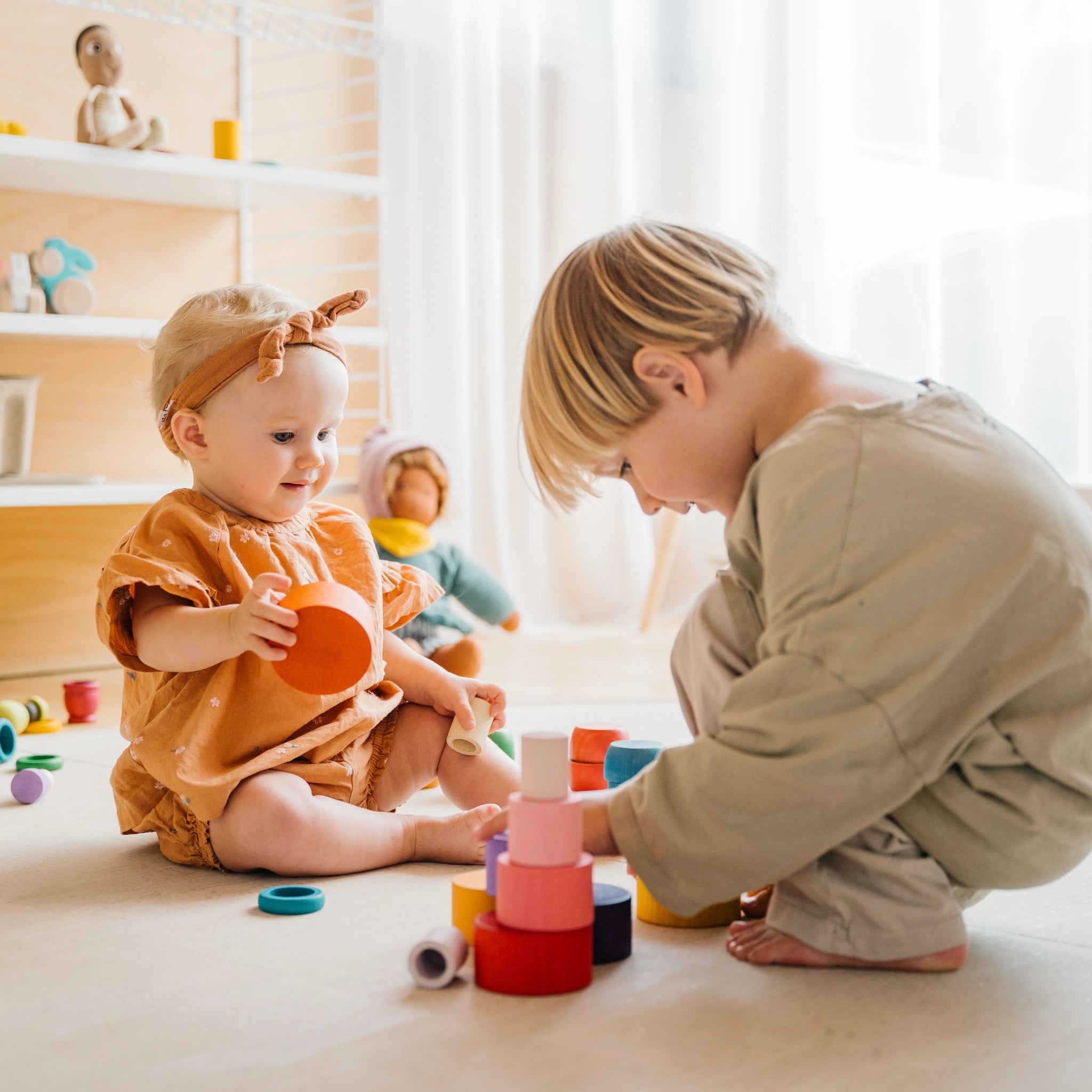 Zwei Kinder spielen mit den Freies Spiel: Nest Bowls, einem Set aus 24 handgefertigten Holzbechern, ideal zum Bauen, Stapeln und Sortieren, aus nachhaltig geforstetem Holz.