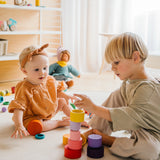 Zwei Kinder spielen mit Freies Spiel: Nest Bowls, einem Set aus 24 handgefertigten Holzbechern, ideal für kreatives Spiel, Bauen und Sortieren, aus nachhaltigem Holz gefertigt.