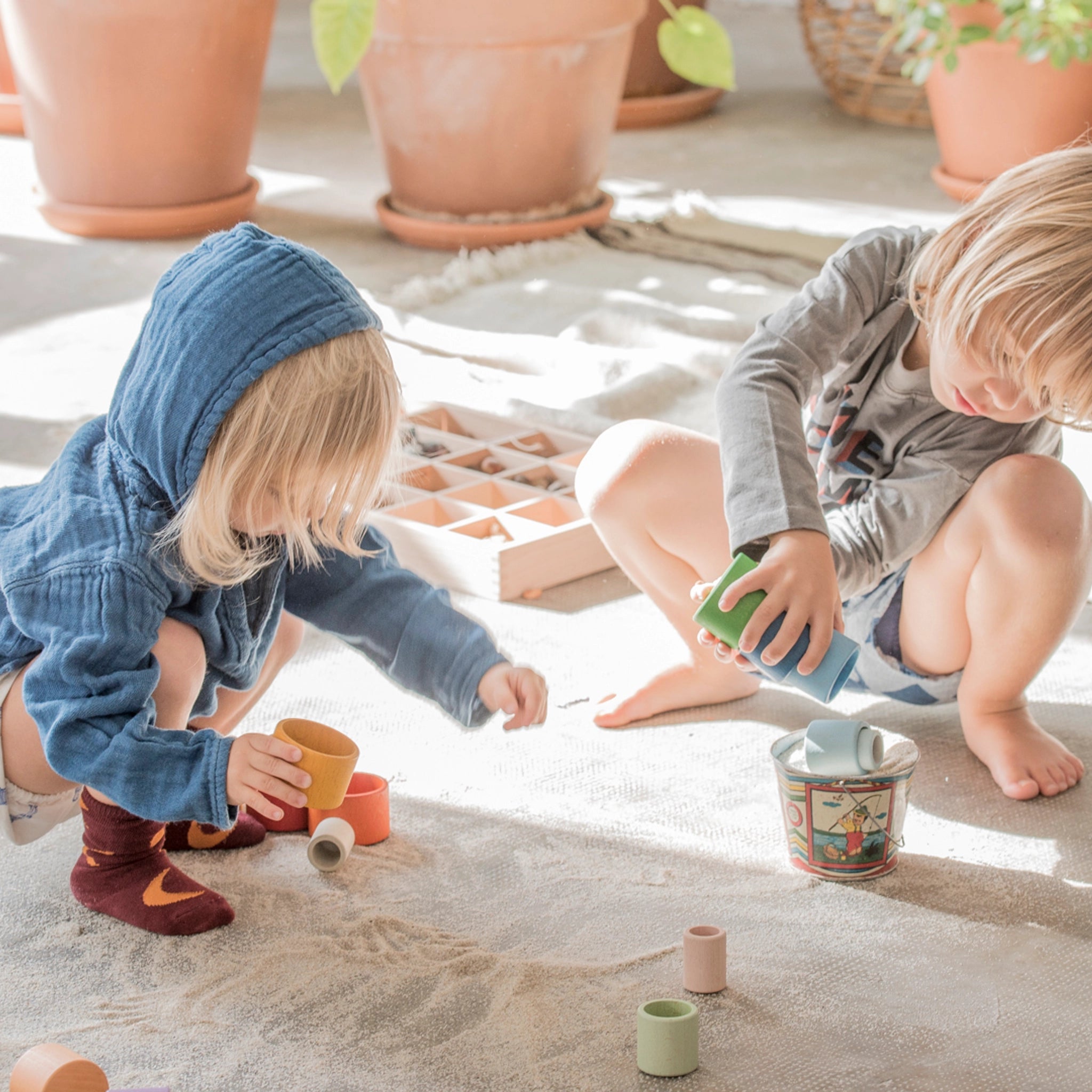 Zwei Kinder spielen mit Freies Spiel: Nest Bowls aus nachhaltig geforstetem Holz, die zum Bauen, Stapeln und Sortieren geeignet sind. Handgefertigt in Spanien, fördern sie kreatives, freies Spiel.