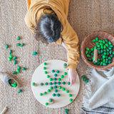 Freies Spiel: Mandala Tree - Ein Kind spielt mit handgefertigten Holzmandalas aus 36 grünen Bäumen, ideal für kreative Kunstwerke aus nachhaltig geforstetem Holz, passend zur modernen und nachhaltigen Ästhetik von KLICKKLACK.