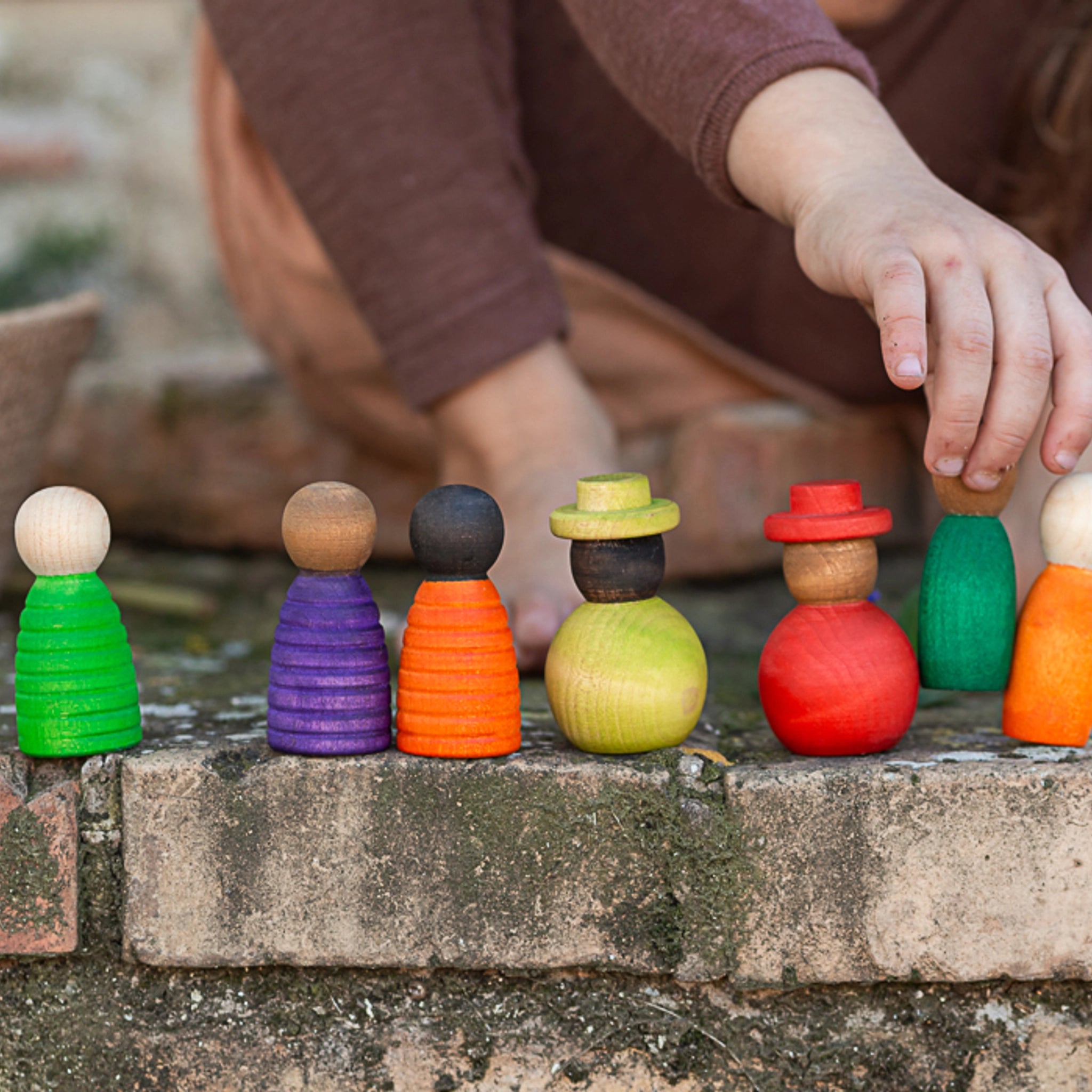 Freies Spiel: Together - Ein Kind spielt mit einem Set aus 12 handgefertigten, nachhaltigen Holzfiguren in verschiedenen Größen und Hautfarben. Perfekt für kreatives, freies Spiel.