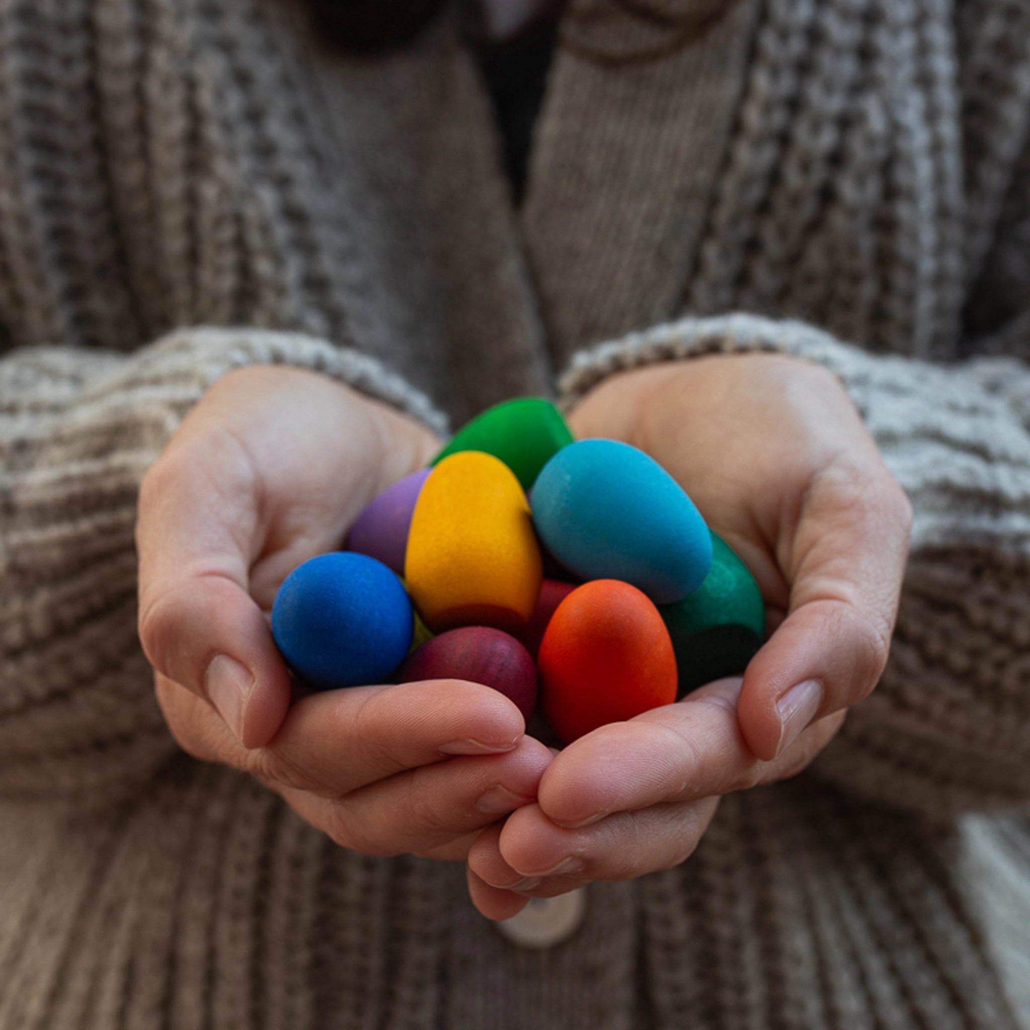 Freies Spiel: Mandala Rainbow Eggs – Eine Hand hält handgefertigte bunte Eier aus Spanien, ideal für kreative Kinderspiele und Mandala-Gestaltung, hergestellt aus nachhaltig geforstetem Holz.