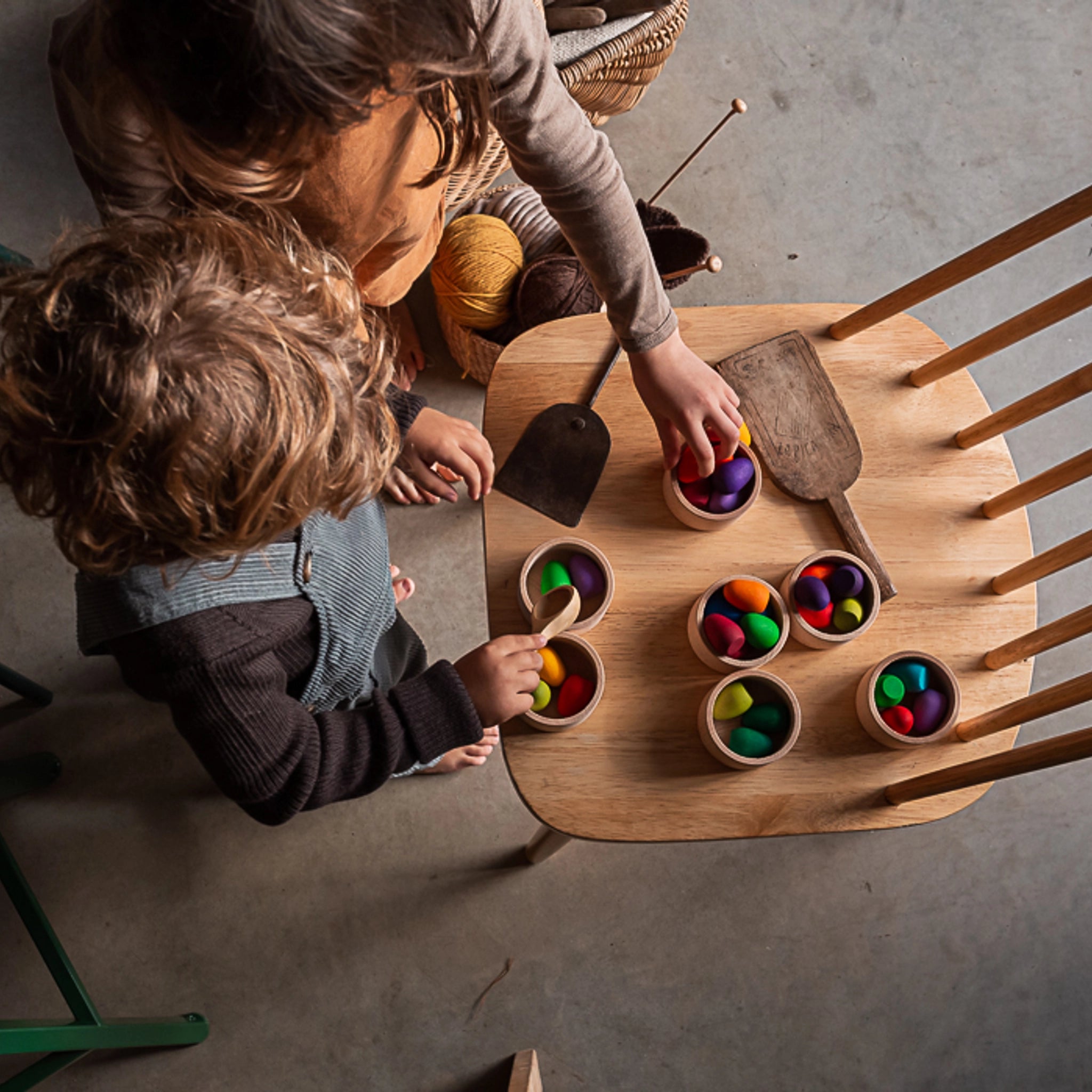 Freies Spiel: Mandala Rainbow Eggs – Zwei Kinder spielen mit handgefertigten, nachhaltigen Holzeiern aus einem Set von 36 Stück, ideal zum Kreieren bunter Mandalas und Kunstwerke.