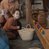 Freies Spiel: Mandala Rainbow Eggs – Eine Gruppe von Menschen sitzt am Boden mit einer Reihe handgefertigter, bunter Holzeier, ideal für kreatives Spiel und nachhaltige Kunstgestaltung.