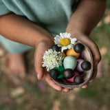 Freies Spiel: Dark Baby Nins - Eine Person hält eine Kokosnussschale mit 6 handgefertigten Baby Nins-Figuren aus nachhaltig geforstetem Holz, ideal für kreatives Kinderspiel, von KLICKKLACK.