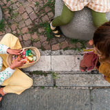 Freies Spiel: Fancy Nins – Eine Gruppe Kinder spielt mit handgefertigten, kunterbunten Fancy-Nins-Figuren aus nachhaltig geforstetem Holz. Perfekt geeignet für kreatives, freies Spiel und fördert Fantasie.