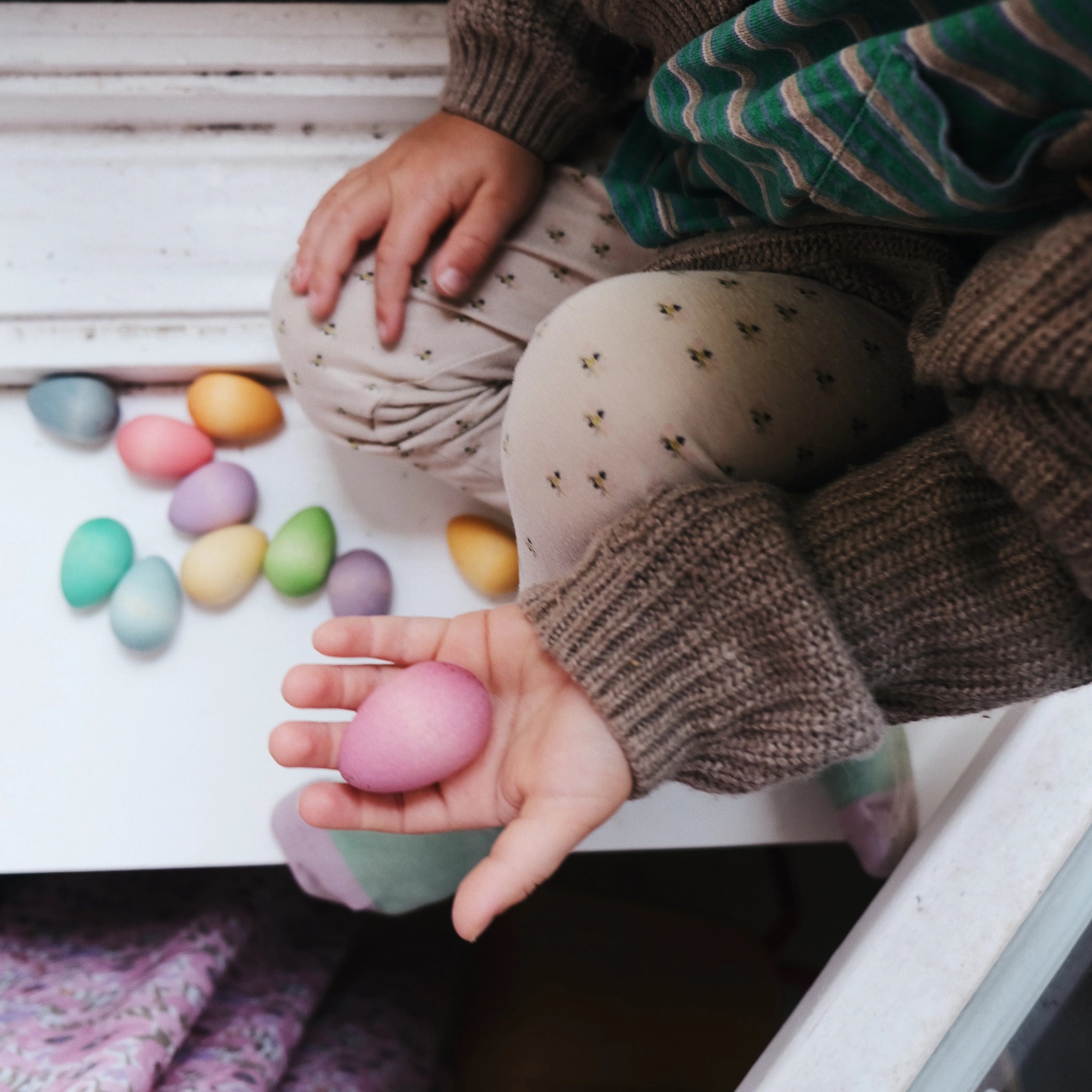 Freies Spiel: Happy Eggs – Eine Hand hält ein handgefertigtes, bunt bemaltes Ei aus nachhaltigem Holz, ideal für kreatives Spielen von Kindern. Hergestellt in Spanien und perfekt für Ostern.