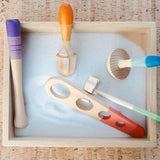 Freies Spiel: Tools - Set aus sechs handgefertigten, bunten Holzwerkzeugen in einer Box mit Sand. Ideal für kreatives Spiel drinnen und draußen, aus nachhaltig bewirtschaftetem Holz, hergestellt in Spanien.