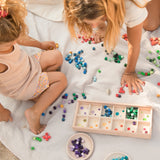 Freies Spiel: Mis and Match - Zwei Mädchen spielen mit über 400 bunten Holzwürfeln in einem handgefertigten Setzkasten aus nachhaltig produziertem Holz, ideal für kreatives, freies Spiel.