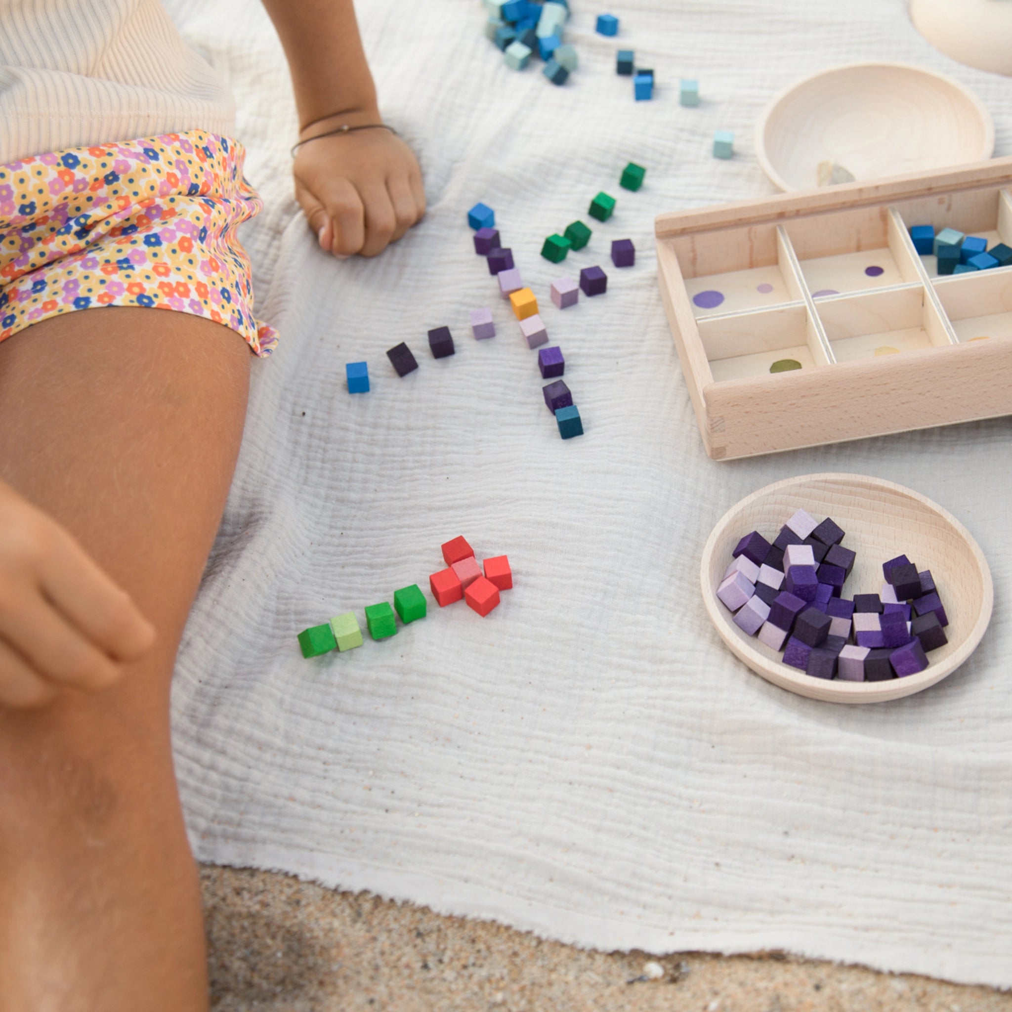 Freies Spiel: Mis and Match - Ein Kind sitzt auf einer Decke mit einem Setzkasten voller bunter Holzblöcke, ideal zum kreativen Spielen. Handgefertigt aus nachhaltig geforstetem Holz, fördert es fantasievolles Spiel.