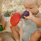 Freies Spiel: Pots – Ein Baby spielt draußen mit nachhaltigen, handgefertigten Holz-Töpfchen, die ideal für kreatives und freies Spiel sind. Perfekt für drinnen und draußen, fördert umweltfreundliche Produktion.