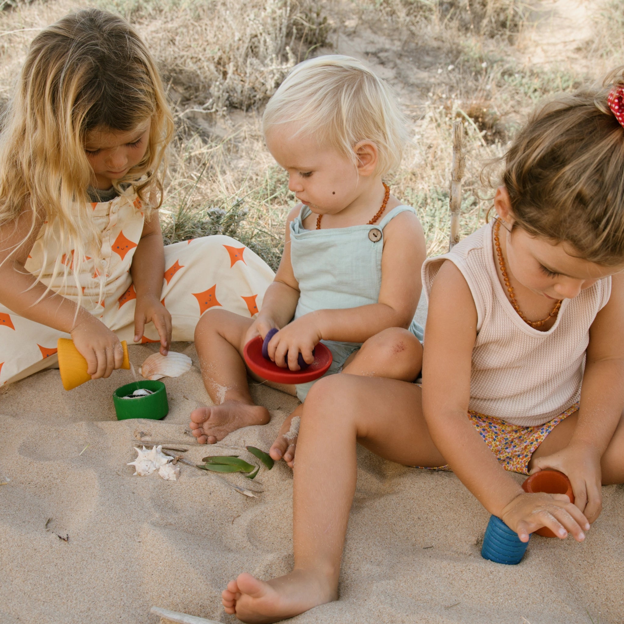 Freies Spiel: Pots – Kinder spielen mit handgefertigten, bunten Holztöpfchen im Sand. Ideal für drinnen und draußen, fördern sie kreatives Spiel. Nachhaltig produziert und aus hochwertigem Holz gefertigt.