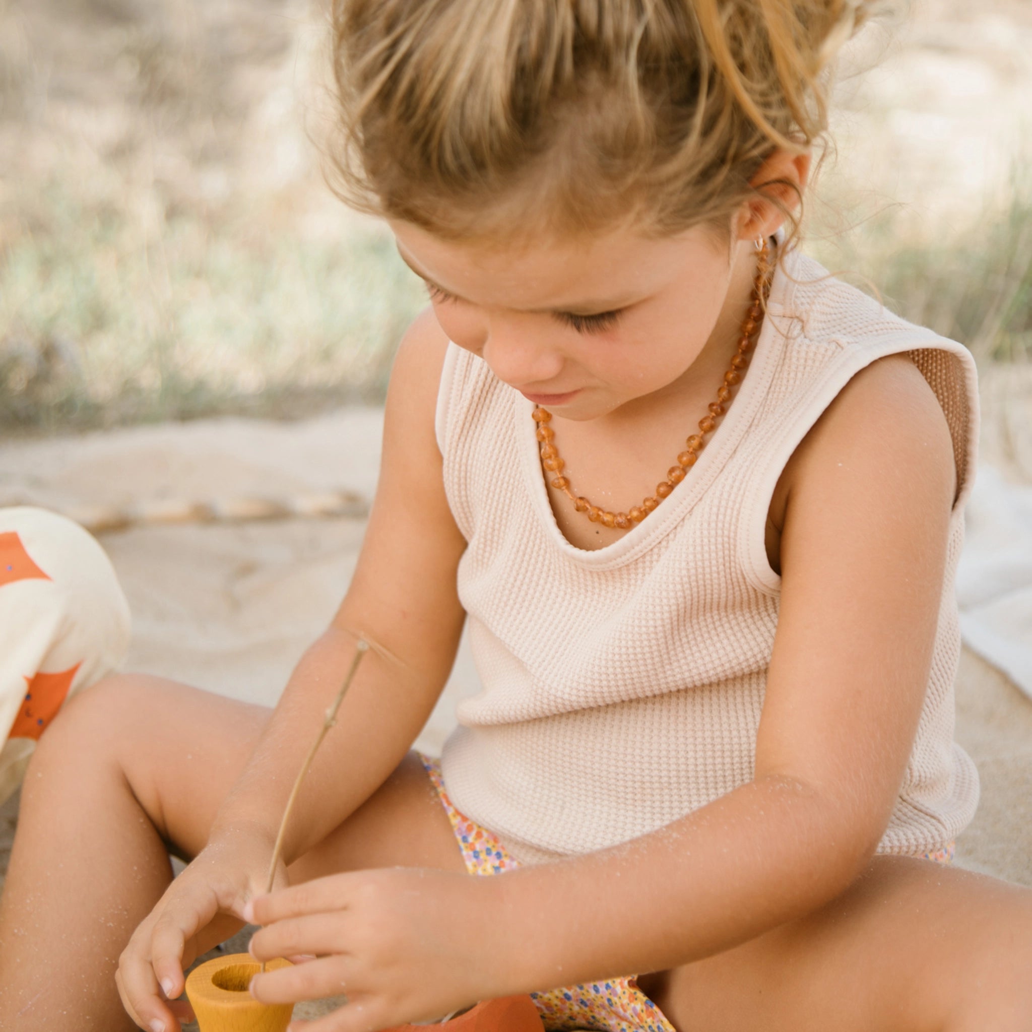 Freies Spiel: Ein Mädchen spielt mit einem Topf aus nachhaltig produziertem Holz, ideal für drinnen und draußen, handgefertigt in Spanien.