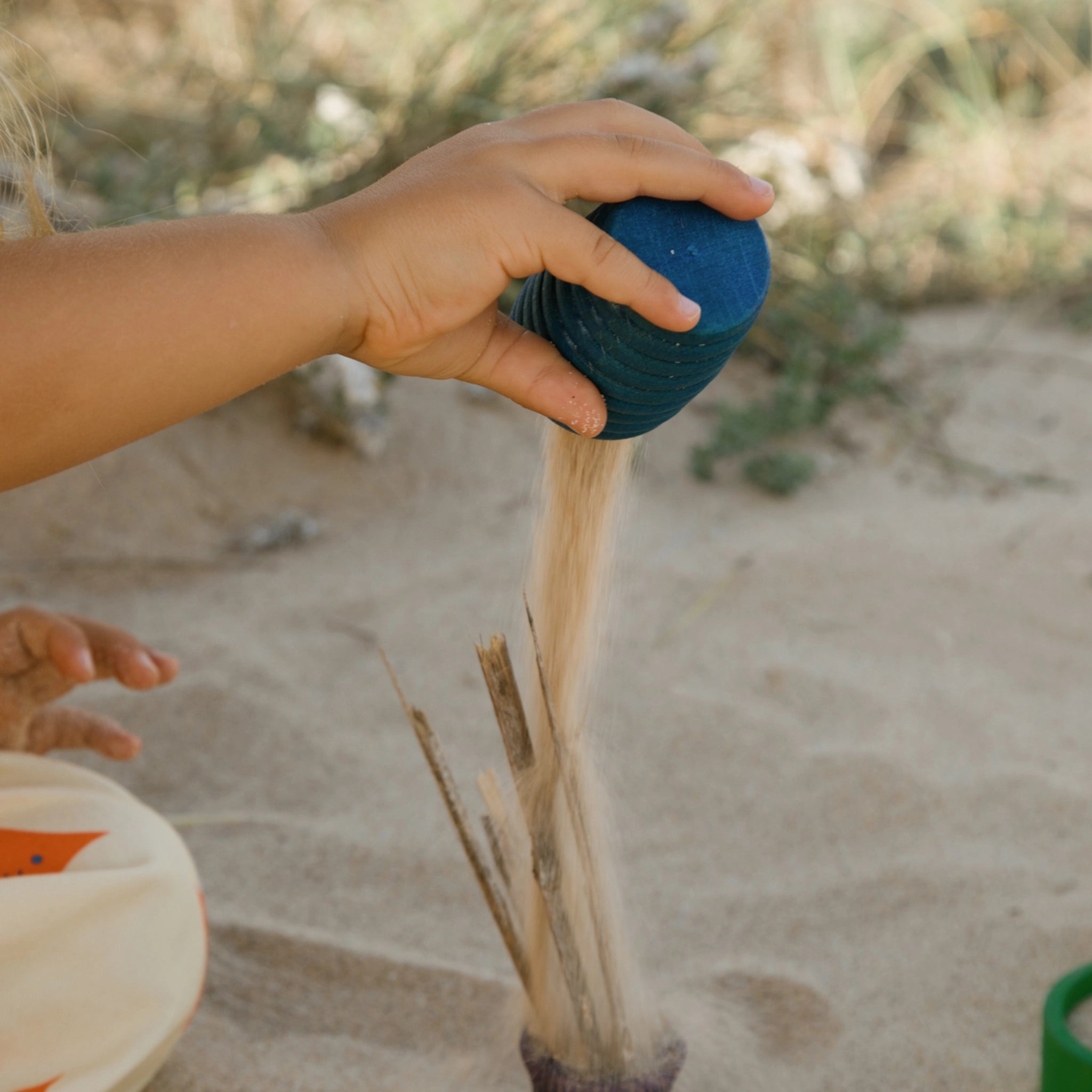 Freies Spiel: Pots aus handgefertigtem Holz, ein Kind füllt Sand in einen blauen Topf. Perfekt für kreatives Spiel im Innen- und Außenbereich, betont nachhaltige Produktion und ästhetisches Design.