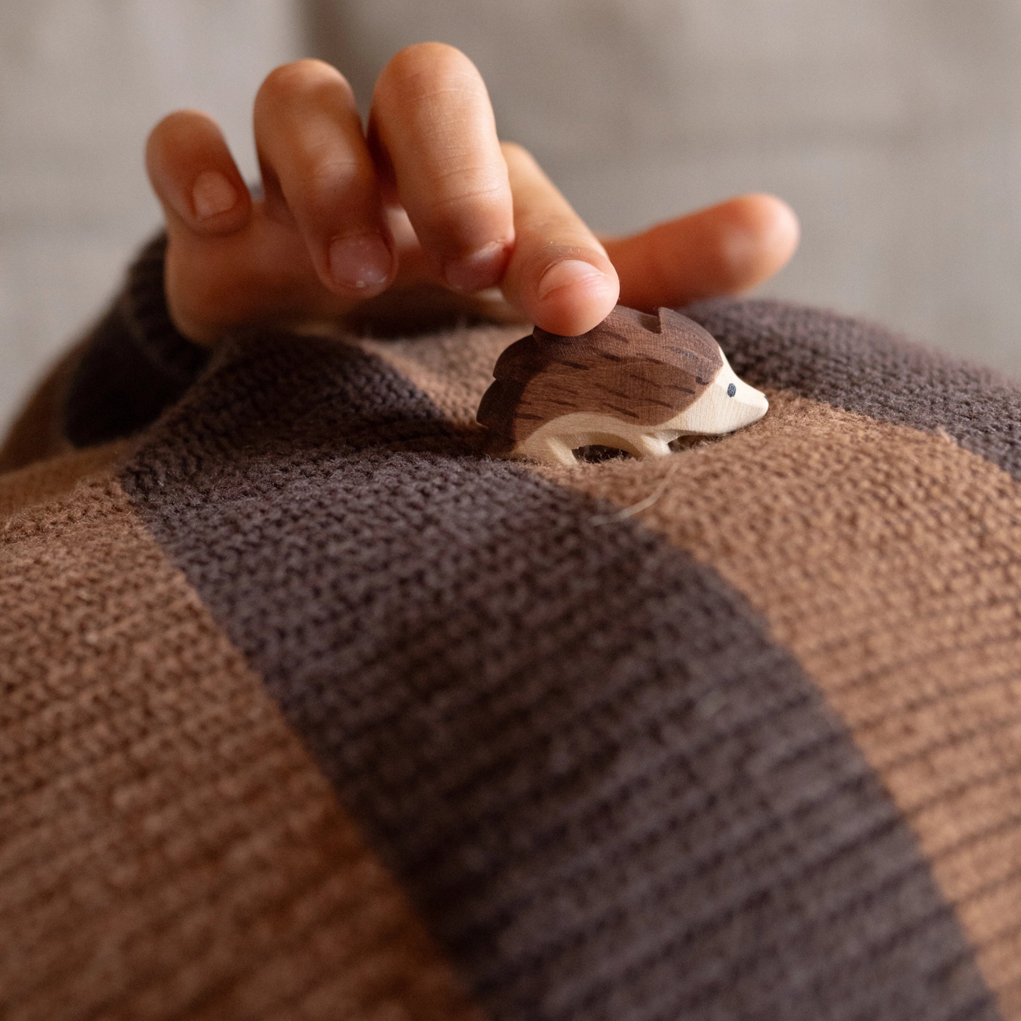 Holzfigur Freies Spiel: Hello autumn! auf braunem Strickstoff, von Kinderhand berührt. Handgefertigt aus nachhaltig geforstetem Holz, Teil einer limitierten Sommerbox von Grapat & Ostheimer.