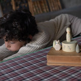 Freies Spiel: Hello winter! zeigt ein Kind, das sich über eine karierte Oberfläche beugt, neben handbemalten Holzfiguren wie einer Eule und Bäumen, aus nachhaltiger Produktion in Spanien und Deutschland.