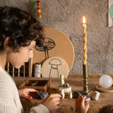 Ein Kind erkundet das Freies Spiel: Hello Winter! Set mit handbemalten Holzelementen und Mineralien, darunter Holzfiguren und ein Kristallball, alle auf einer rustikalen Holzoberfläche arrangiert.