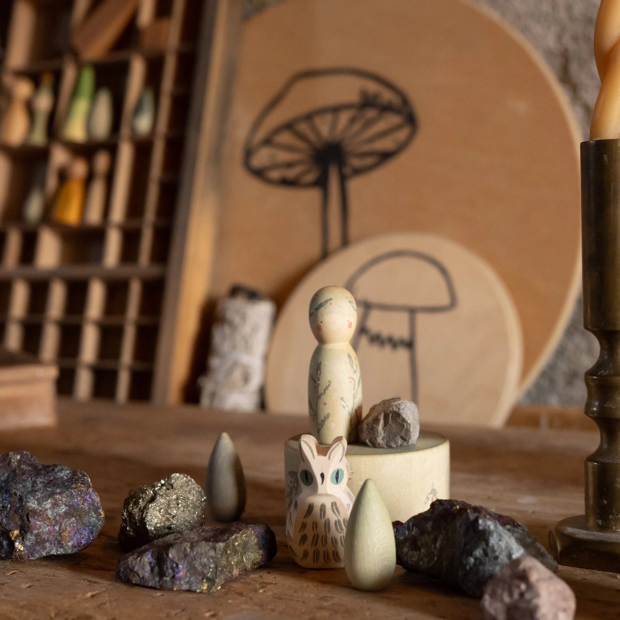 Freies Spiel: Hello winter! zeigt ein Set aus fünf handbemalten Holzelementen, darunter ein Holzpegelfigur, ein Eulenfigur und Holzformen, die auf einem Tisch mit Mineralien arrangiert sind.