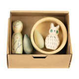 Freies Spiel: Hello Winter! zeigt ein handgefertigtes Holzspielset mit einer runden Holzfigur, zwei baumförmigen Teilen, einer flachen Eulenfigur und einer Holzschale, inspiriert von der Natur und Nachhaltigkeit.