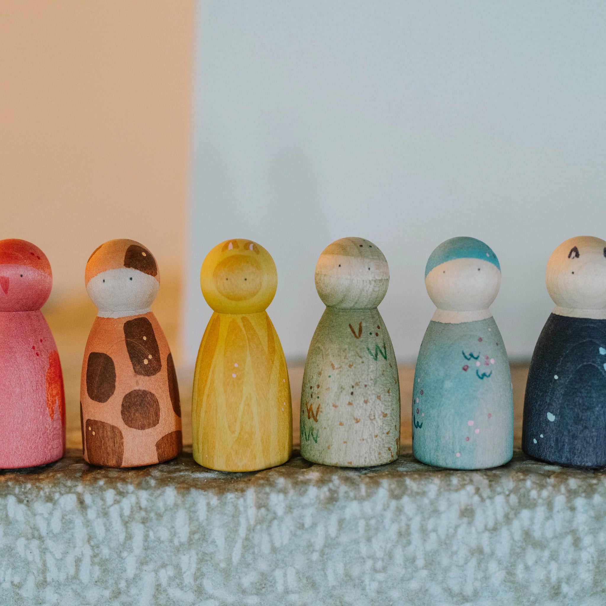 Sechs handbemalte Holzfiguren Freies Spiel: Animal Crew stehen in einer Reihe auf einem Regal. Jede Figur zeigt ein einzigartiges Design.