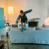 Kinder spielen lebhaft auf einem hellgrauen Sofa, während der ältere auf der Rückenlehne balanciert. Freies Spiel: Warm Mandala Mix fördert kreative Entfaltung in einem stilvollen, gemütlichen Wohnzimmer von KLICKKLACK.