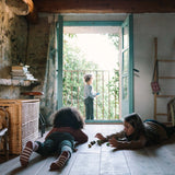 Zwei Kinder spielen auf dem Boden mit Freies Spiel: Animal Crew, während ein drittes Kind auf dem Balkon steht. Die Szene strahlt Ruhe und Natürlichkeit aus, passend zur nachhaltigen Ästhetik von KLICKKLACK.