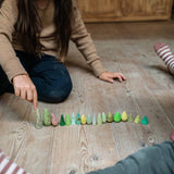 Zwei Kinder spielen mit Freies Spiel: Animal Crew auf einem Holzboden. Die natürlichen Holzstücke, die kleinen Bäumen ähneln, fördern kreatives, offenes Spiel, passend zu KLICKKLACKs nachhaltiger Ästhetik.