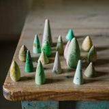 Freies Spiel: Animal Crew – Eine Sammlung aus kleinen, kegelförmigen Holzblöcken in Pastell- und Grautönen, die stilisierte Bäume bilden. Perfektes Beispiel für nachhaltiges Design von KLICKKLACK.