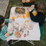 Zwei Kinder sortieren Pilze auf einem Tisch mit dem Produkt Freies Spiel: Forest Tree, umgeben von einer Korb voller Pfifferlinge, Holzschalen mit Pilzen und kleinen Holzutensilien, passend zum nachhaltigen Design von KLICKKLACK.