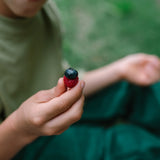 Ein Kind hält eine kleine Beeren-Stapelung in der Hand, bestehend aus einer Himbeere mit einer Blaubeere darauf. Dies repräsentiert das Produkt Freies Spiel: Fruits von KLICKKLACK.