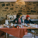 Zwei Mädchen, die mit dem Freies Spiel: Bakes Set in einer rustikalen Küche backen, mit Teigrollen, Schokoladenstücken und einer gemütlichen Atmosphäre, die handwerkliche Tradition und modernes Design von KLICKKLACK vereint.