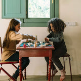 Zwei Kinder spielen mit dem Freies Spiel: Dishes Set an einem Tisch, inszenieren eine imaginäre Teeparty mit kleinen Schalen und Objekten, die die Kreativität fördern.