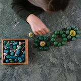 Freies Spiel: Moonlight – Oberansicht zeigt Hände, die hölzerne Teile um Äpfel arrangieren. Links eine offene Box mit weiteren Teilen. Eine Darstellung künstlerischer, spielerischer Holzkomposition von KLICKKLACK.