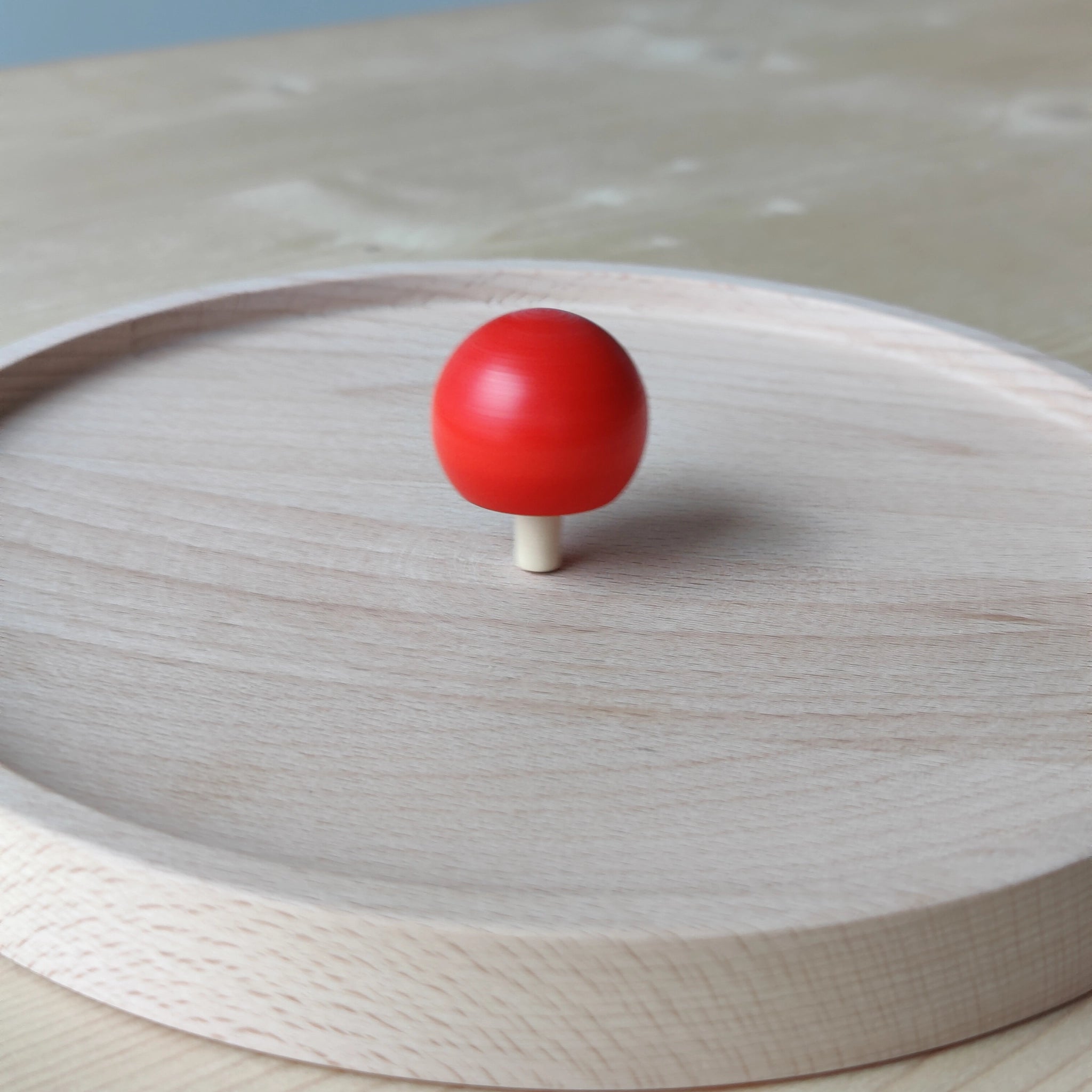 Umkehrkreisel rot: Ein roter Kreisel aus massivem Ahornholz, der sich beim Drehen auf den Kopf stellt, handgefertigt in einem deutschen Familienbetrieb. Perfekte Balance aus Ästhetik und nachhaltigem Design.