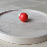 Kreiselteller aus massivem Buchenholz mit erhöhtem Rand, der ein Wegrollen verhindert, präsentiert auf einem Tisch. Perfekt zum Spielen mit Holzkreiseln, handgefertigt in Deutschland für nachhaltigen Spaß.