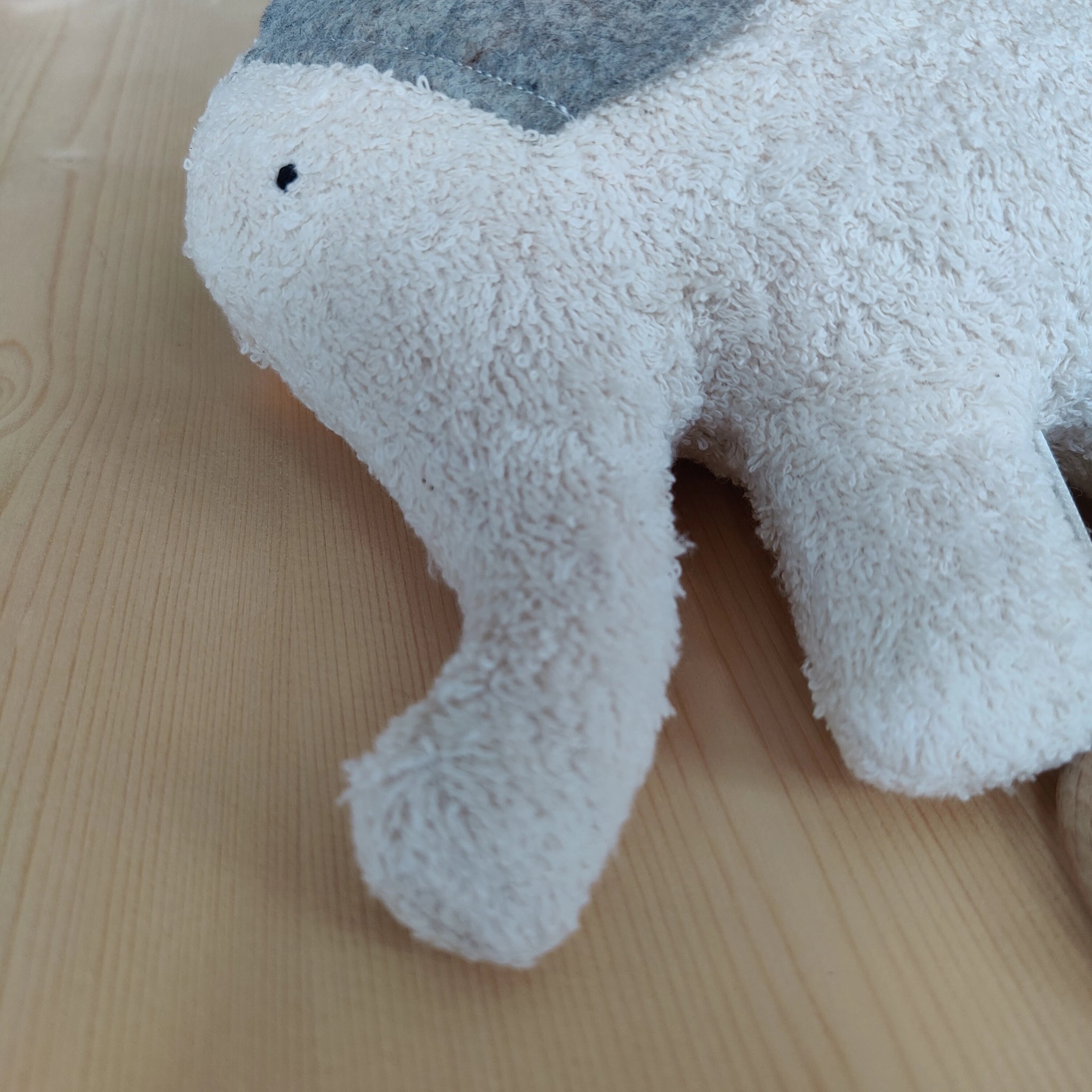 Spieluhr: Elefant, ein weiches Stofftier aus Bio-Baumwolle und Schafwolle, auf einem Tisch. Es ist ein hochwertiges, in Deutschland gefertigtes Produkt, ideal für ein sanftes Einschlafritual.