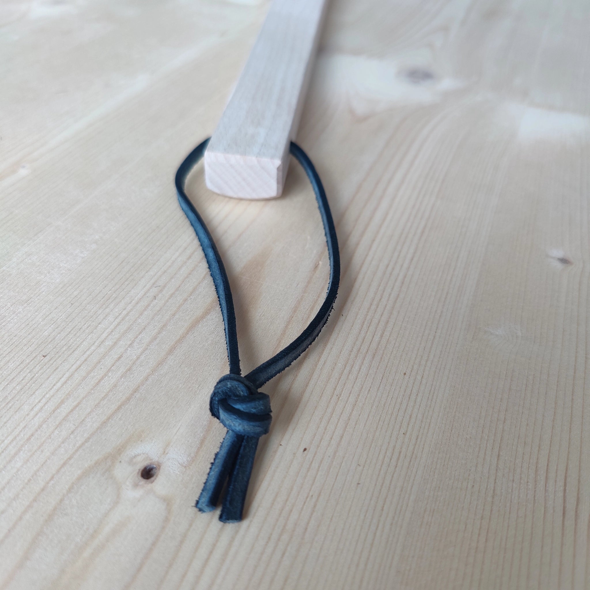 Großer Schuhlöffel aus robustem Buchenholz mit 66cm Länge, überzogenem Lederband zum Aufhängen, präsentiert auf einem hellen Holztisch. Handgefertigt in der Schweiz, bietet er stilvolle Funktionalität und Langlebigkeit.