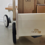 Holzfahrzeug: Lastenrad aus Buchen- und Ahornholz mit einer stabilen, kippsicheren Konstruktion. Nahaufnahme zeigt den Holz-Logo-Brand Cargo bike und beladene Pappkartons im Vorderradkorb.
