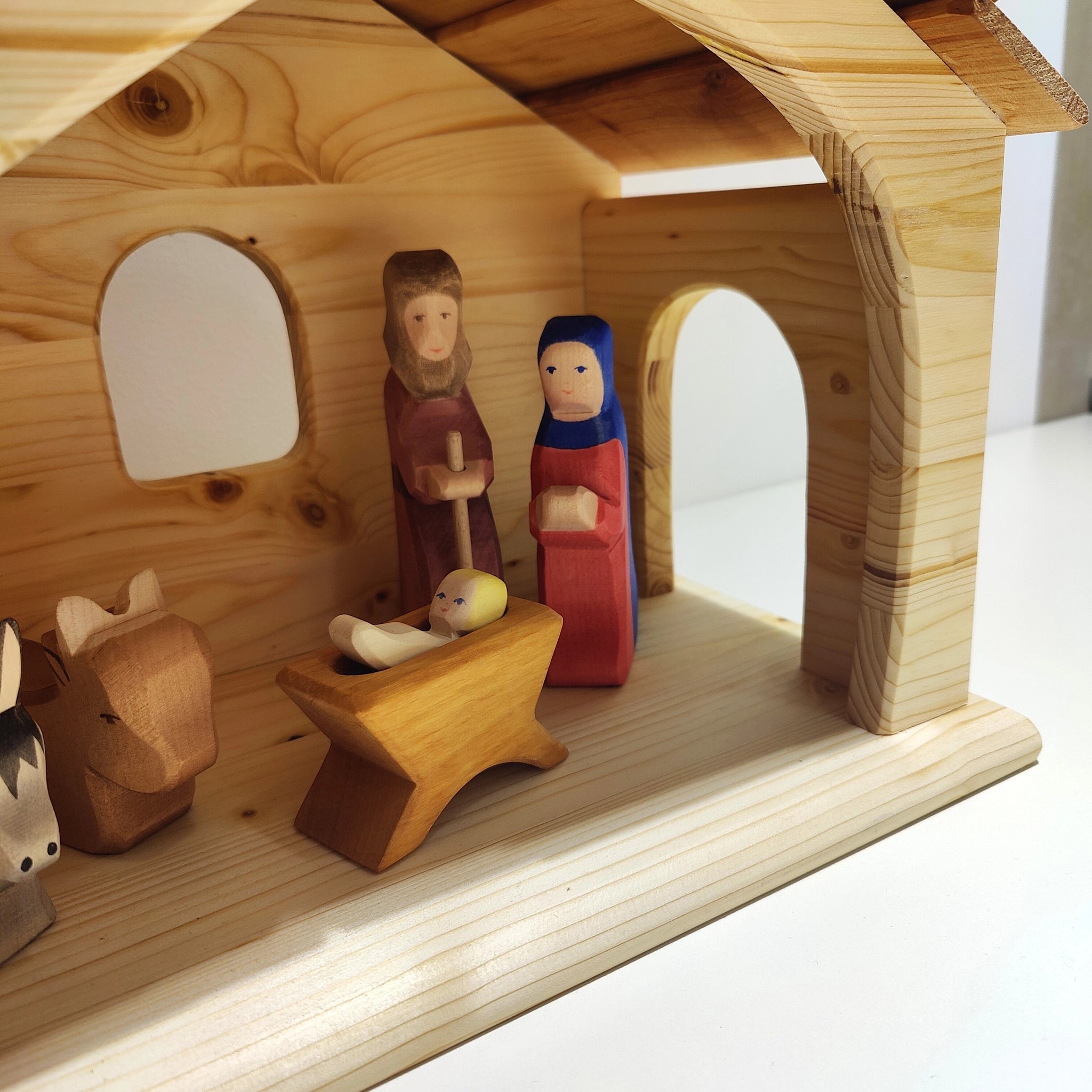 Krippe aus massivem Fichtenholz mit handgeschnitzten Figuren von Maria, Josef, Jesuskind und Tieren. Ausgestattet mit robustem Schindeldach und Fenster, hergestellt in einer kleinen deutschen Manufaktur.